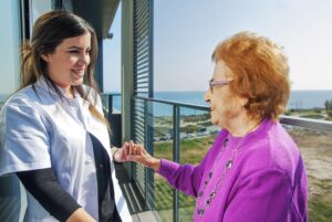 Mujer mayor junto a su cuidadora en el balcon